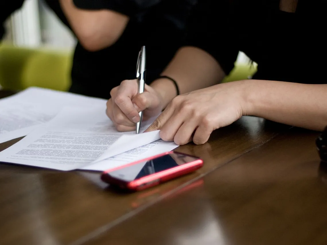 A person signing a document with a pen